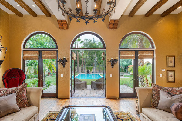 سه در بزرگ با طراحی قوسی شکل در فاصله بین حیاط و اتاق نشیمن، چشم انداز فوق العاده زیبایی درست کرده اند.