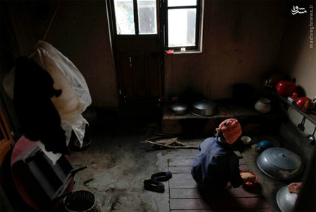 یک زن کشاورز که در سیل سال گذشته خسارت دیده در حال غذا درست کردن است.